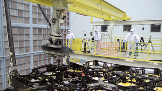 Engineers at NASA Goddard Space Flight Center install the first mirror onto the Webb Telescope.