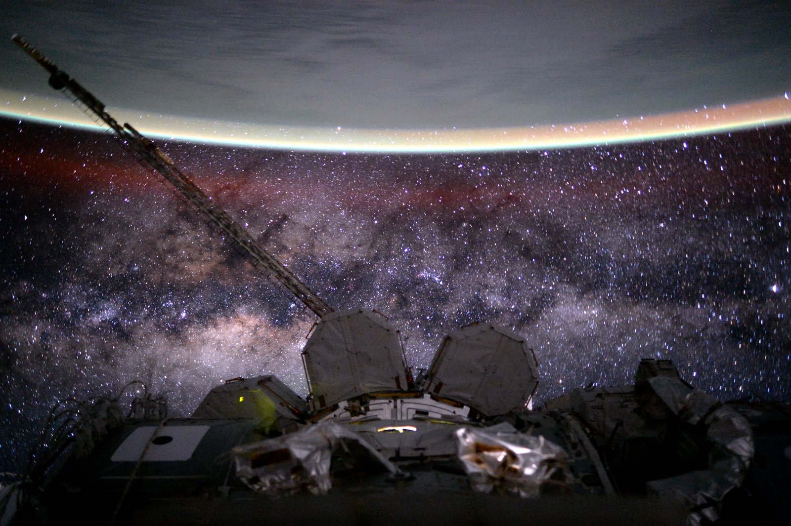 PhotographSince November 2000, people have been living continuously on the International Space Station. To celebrate humanity's 15th anniversary off planet Earth, consider this snapshot from space of our galaxy and our home world posing together beyond the orbital outpost. The Milky Way stretches below the curve of Earth's limb in the scene that also records a faint red, extended airglow. The galaxy's central bulge appears with starfields cut by dark rifts of obscuring interstellar dust. The picture was taken by Astronaut Scott Kelly on August 9, 2015, the 135th day of his one-year mission in space.Credit: NASA/Scott Kelly