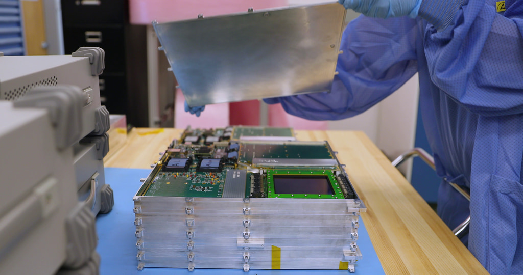 Carolyn Kierans, principal investigator for the ComPair balloon mission at NASA’s Goddard Space Flight Center in Greenbelt, Maryland, works on the instrument in this video. First, she assembles a layer of the tracker, which is housed in an aluminum casing. Next, she shows one of the tracker’s silicon detectors. Then she takes the lid off the tracker.Credit: NASA/Sophia Roberts