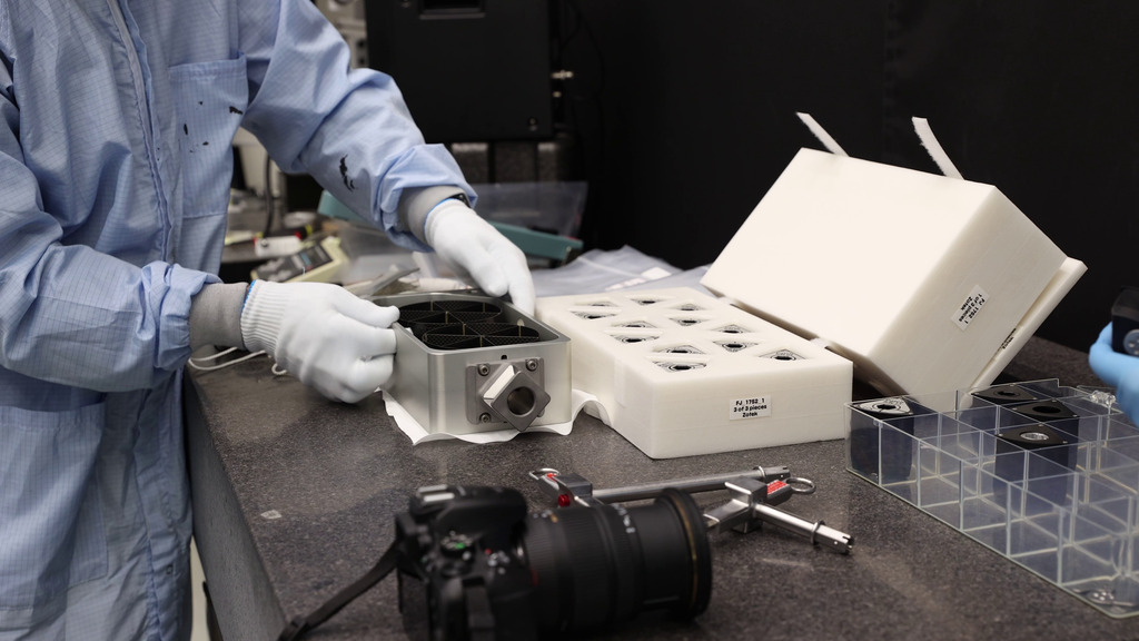 In this video, Keith Gendreau, Steve Kenyon, Lucas Widner, Lauren Maples, and Christensen Hardcastle conduct tests on the NICER patch kit in a clean room at Goddard. 

0:00 Gendreau, Widner, Maples, and Hardcastle enter the clean room and begin to put on their clean suits. 0:21. Hardcastle examines the NICER caddy, which will hold the patches. He checks that the micro square fixture at the end fits different attachments found on an astronaut’s spacesuit. 0:45 Gendreau points out some features of the sunshades inside the caddy, which are flight spares. 1:00 Widner checks that the caddy can be tethered to a spacesuit. 1:33 Hardcastle removes the tethers. 1:49 Widner explains to the NICER team how the tethers will be used during the spacewalk. 2:04 Hardcastle removes the tether again. 2:09 Widner checks that the T-handle tool can pick up, insert, and lock patches into the caddy. 2:36: Widner continues placing patches into the caddy. 2:43 Hardcastle checks the caddy and patches for rough edges while wearing a special pair of gloves. 3:46 Shot of the T-handle tools on a lab bench. 3:52 Maples removes the caddy from its foam packing case and places it on the lab bench. 4:13 Widner shakes the caddy gently to check to see if there are any loose parts. 4:38 Widner flips the caddy upside down and shakes it again. 4:59 Widner inserts patches into the caddy using the T-handle tool. 5:34 Widner removes the patches from the caddy using a shorter version of the T-handle tool. He hands them to Hardcastle for a sharp-edge check, who then places them in the foam packing case. 6:06 A patch with the T-handle tool inserted rests on the lab bench. 6:14 Widner points out features of the T-handle tool. 6:19 Maples removes patches from the packing case and inserts them into the caddy. 6:45 Hardcastle provides the result of the sharp-edge test. 6:57 Hardcastle examines the packing case and takes notes. 7:02 Slow motion shots of the team standing around the table with the caddy. 7:34 Slow motion shot of Widner shaking the caddy. 7:55 Slow motion shot of Kenyon and Gendreau looking at the patches assembled on the lab table. 

Credit: NASA/Sophia Roberts and Scott Wiessinger